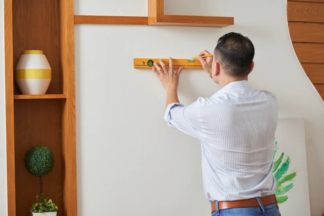 Man Decorating Wall With Picture