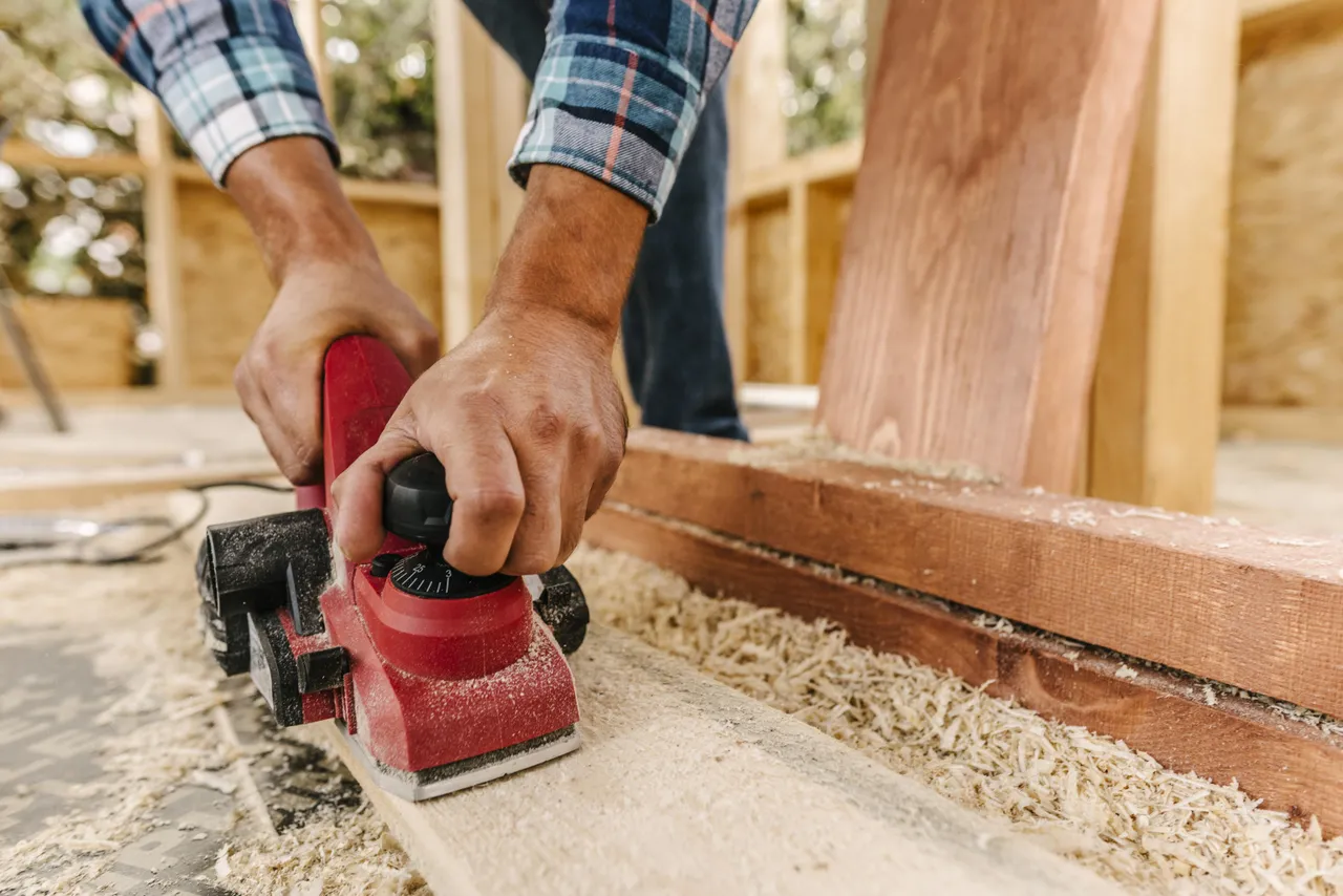 Carpenter Sanding Down Wood Piece